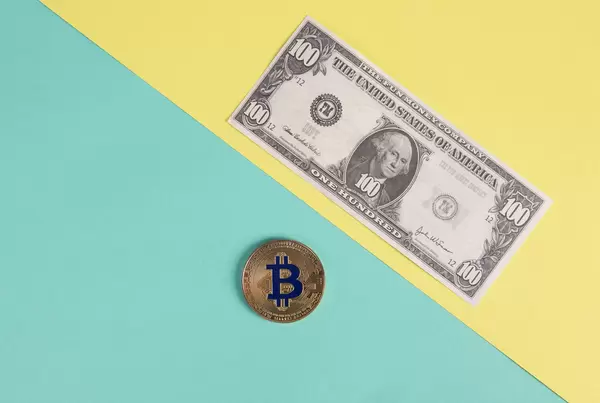 Golden Bitcoin coin and  one hundred dollar banknote