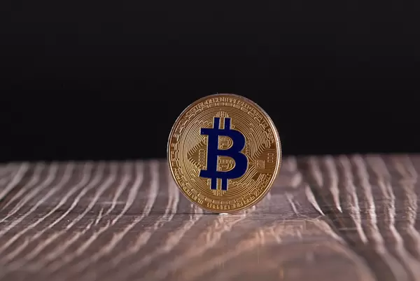 Golden Bitcoin coin on wooden table