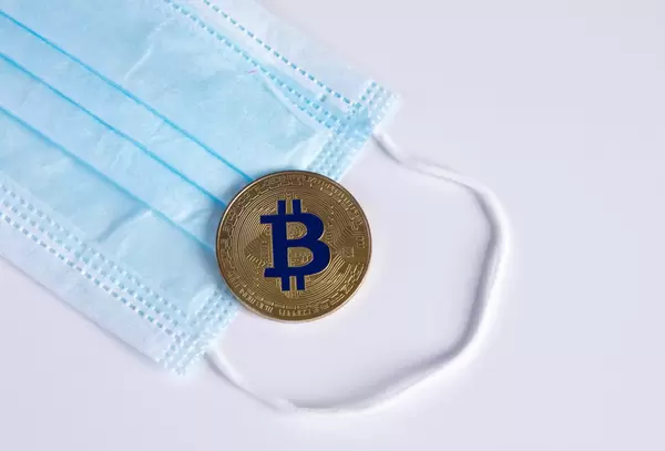 Golden Bitcoin with protective face mask on white background