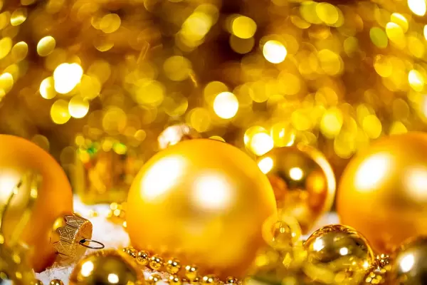 Golden christmas tree spheres in the snow in front of golden background