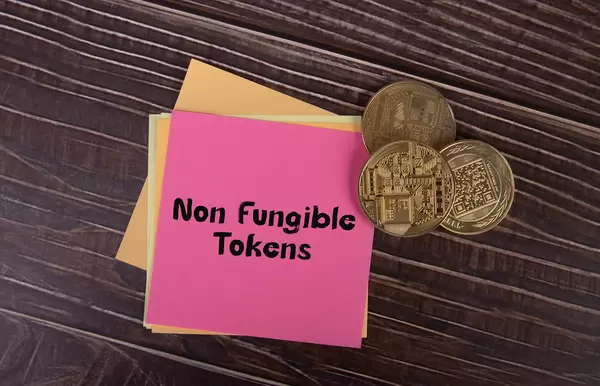 Golden coins and sticky notes with Non Fungible Tokens tex