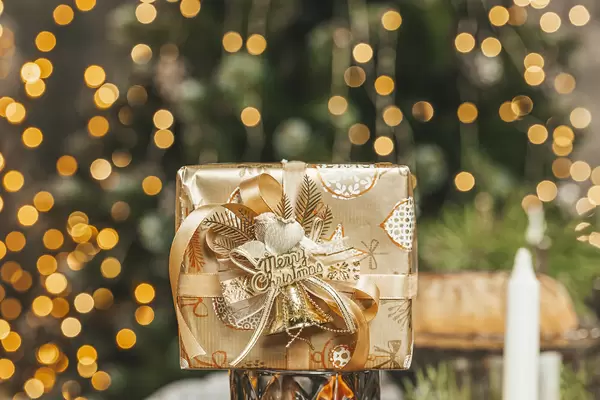 Golden present on a blurry background of a christmas room with garlands