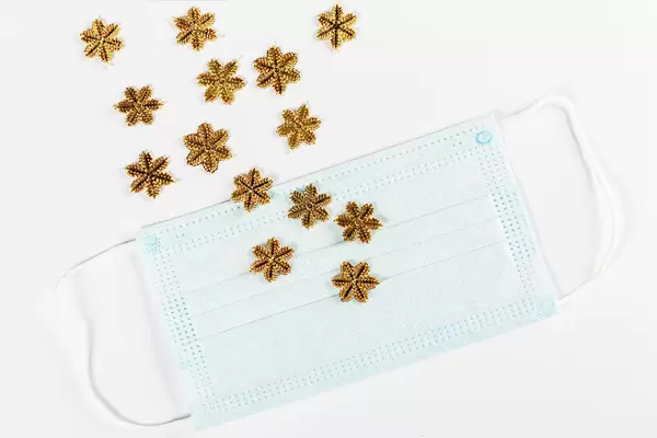 Golden snowflakes scattered on medical mask and white background