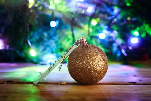 Golden textured Xmas bauble over decorated Christmas tree