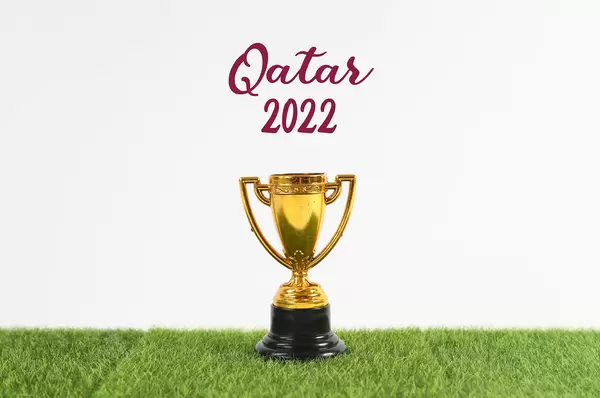 Golden trophy with Qatar 2022 text on green grass
