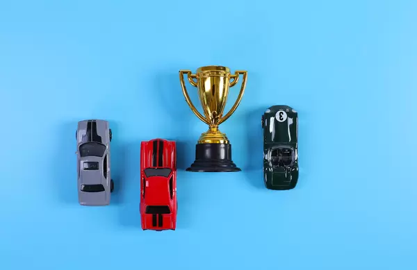 Golden trophy with toy racing cars on blue background