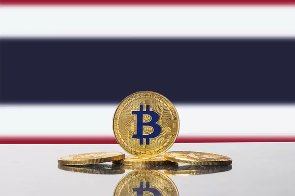 Goldene Bitcoin-Münzen vor der Flagge des südostasiatischen Königreichs Thailand
