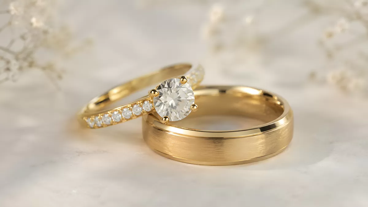 Goldene Eheringe mit Diamant auf Marmor