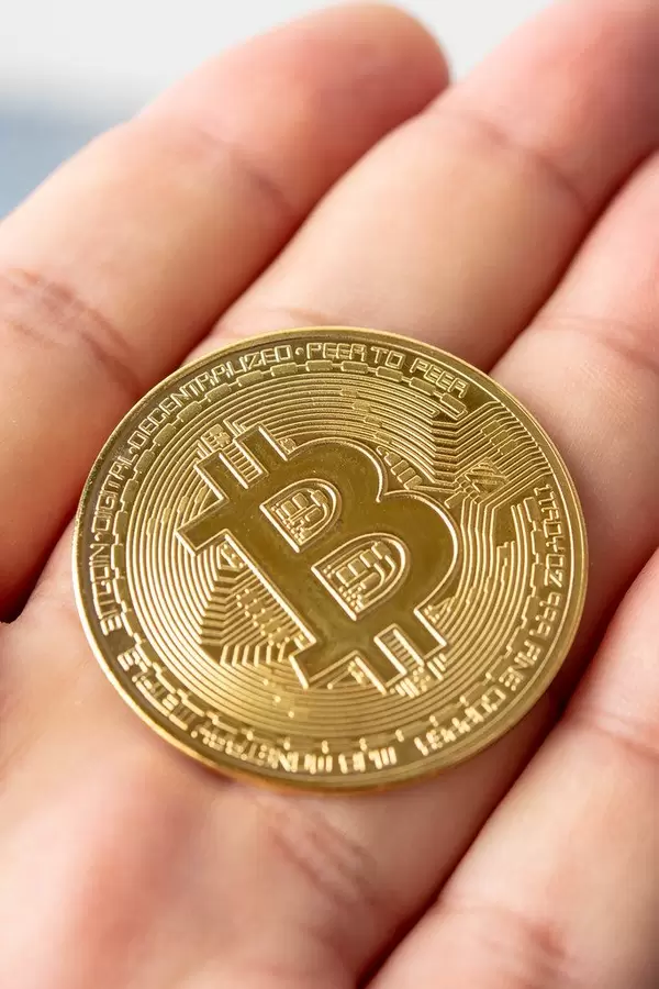 Goldene Metal-Bitcoinmünze liegt auf der flachen Hand