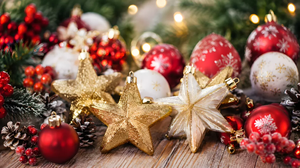 Goldene Sterne und rote Weihnachtskugeln auf Holz