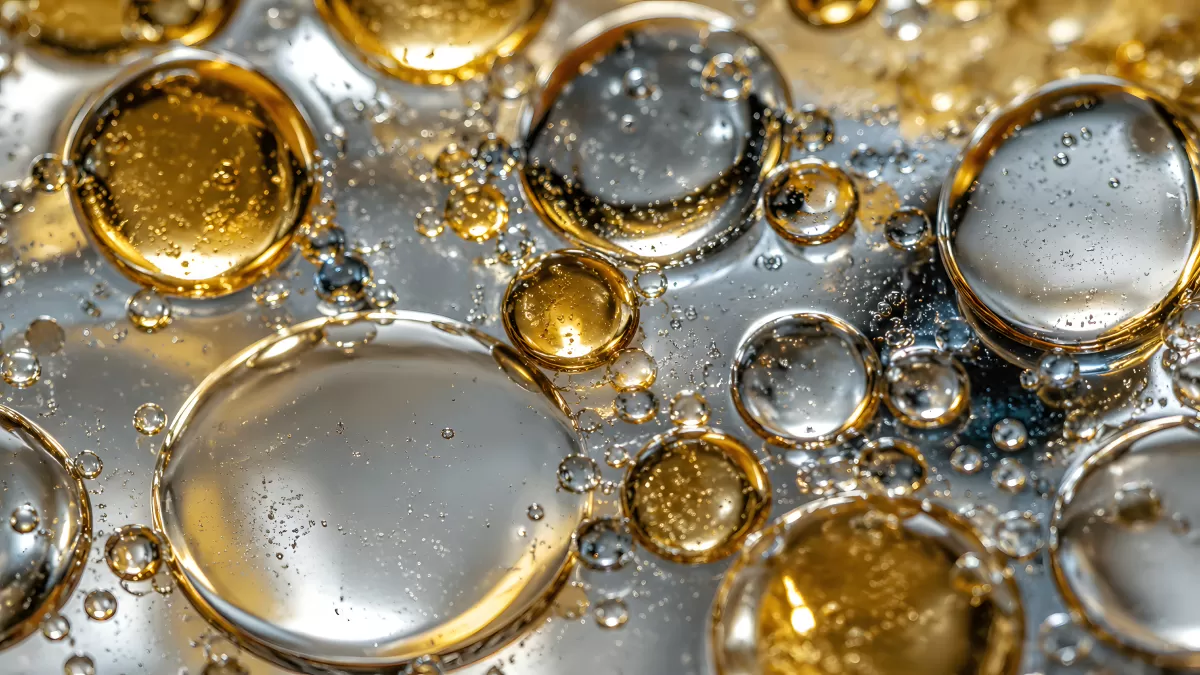 Goldene und silberne Öltropfen auf Wasseroberfläche