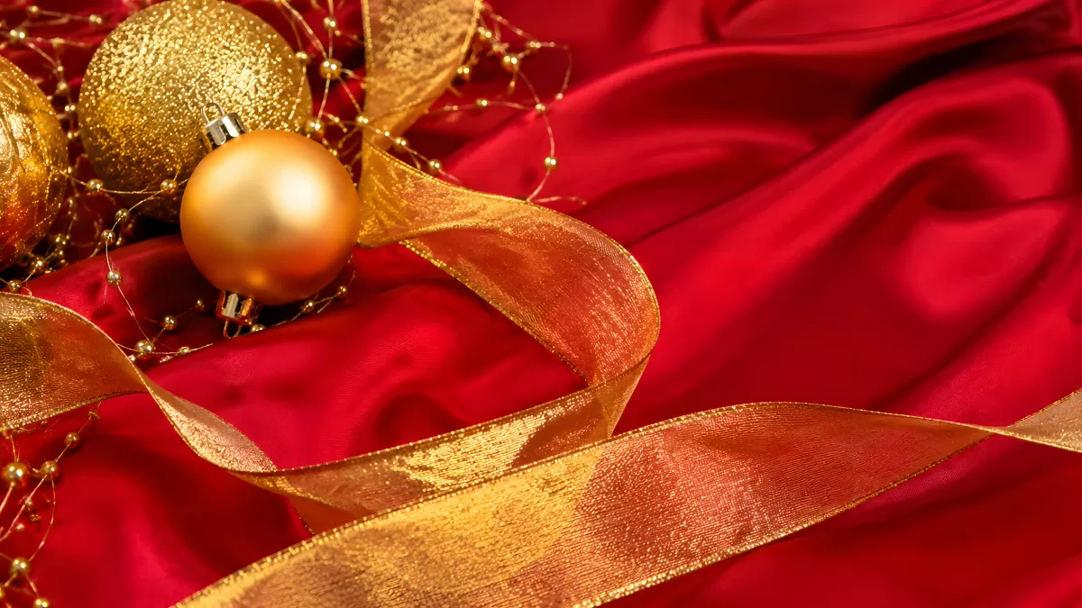 Goldene Weihnachtskugeln auf rotem Seidenstoff