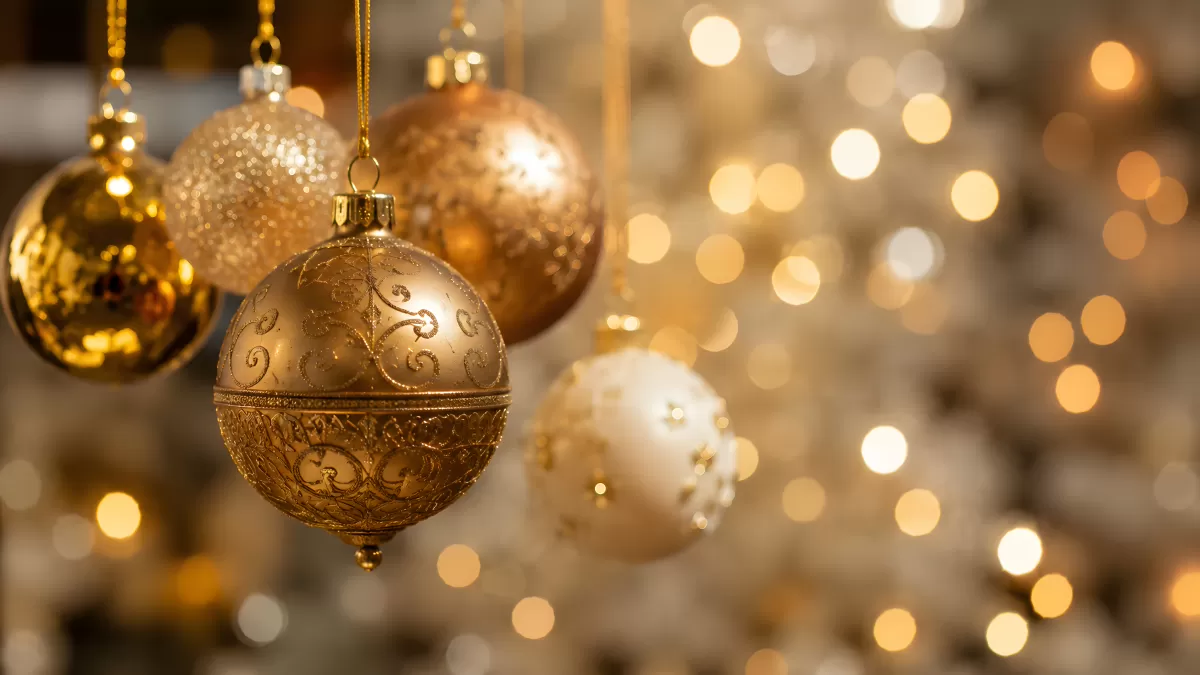 Goldene Weihnachtskugeln hängen vor Bokeh-Lichtern