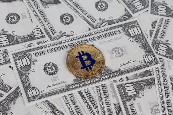 Goldener Bitcoin liegt auf verteilten US-Dollar Noten