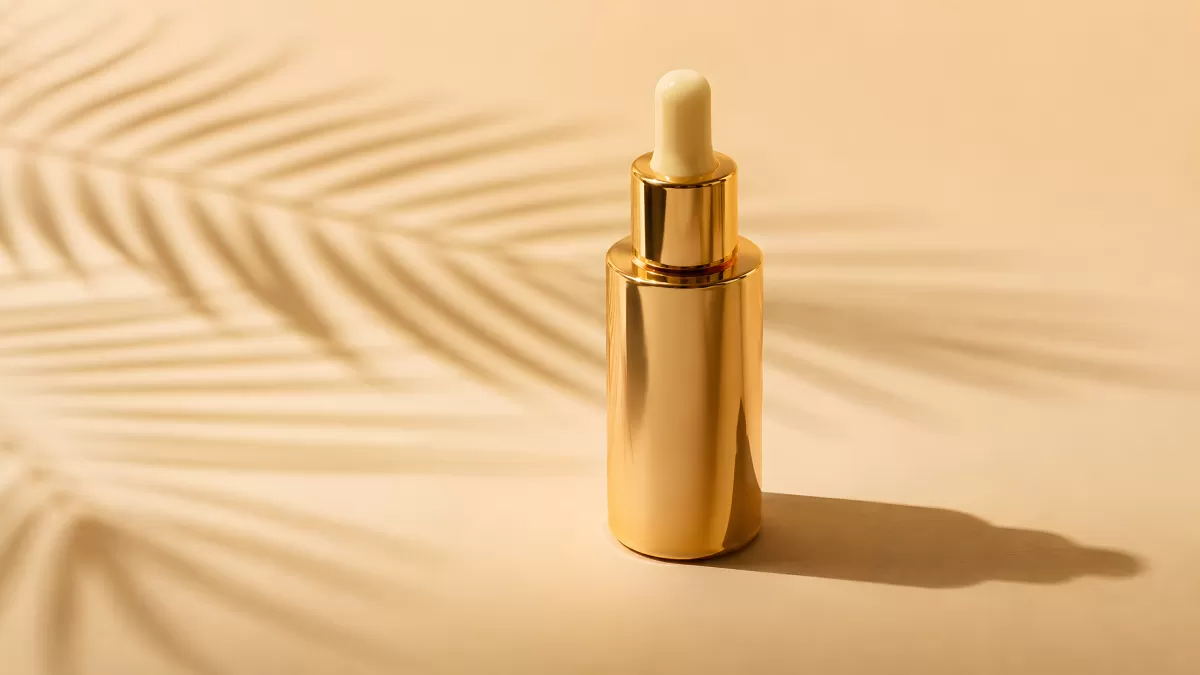 Goldener Kosmetik-Dropper auf beigem Hintergrund