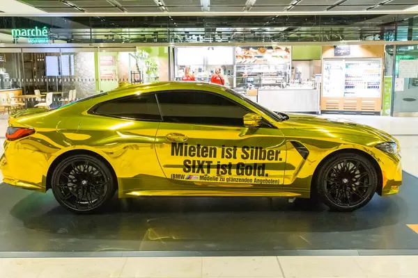 Goldenes Auto mit Schrift "Mieten ist Silber. SIXT ist Gold": Werbung für Mietwagen am Flughafen BER