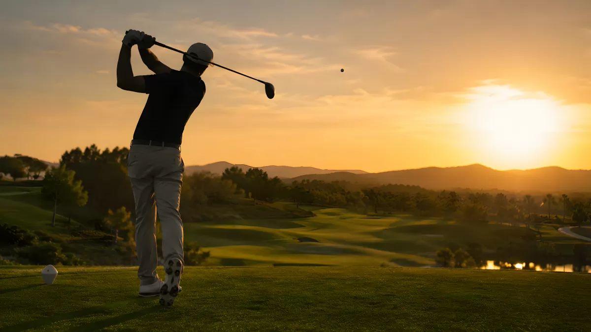 Golfspieler schlägt Ball bei dramatischem Sonnenuntergang