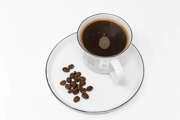 Good morning with a black coffee in a white cup with coffee beans on a white plate on white background