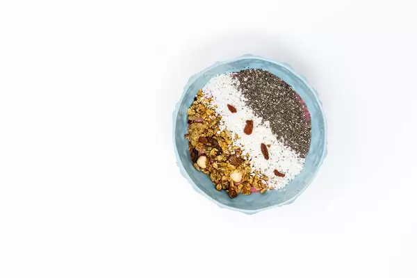 Granola Nuss Knuspermüsli mit Kokosraspeln, Chiasamen und Gojibeeren in Streifenlage in einer Schüssel - von oben