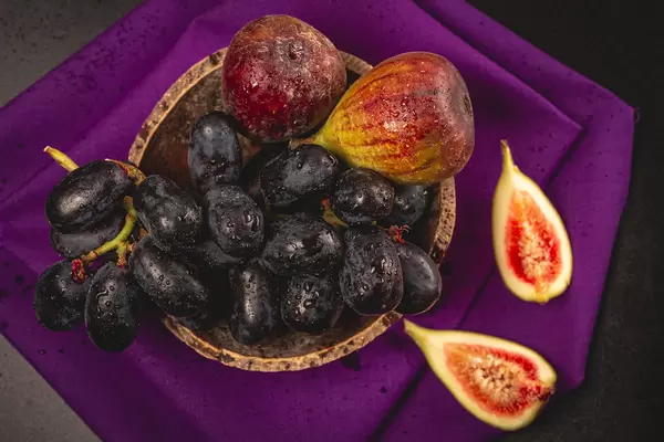 Grapes and dates with water drops on a dark background, top view