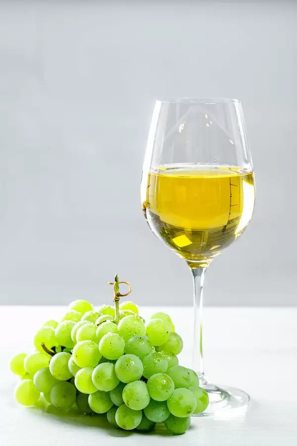 Grapes and white wine glass on a wooden table, front view