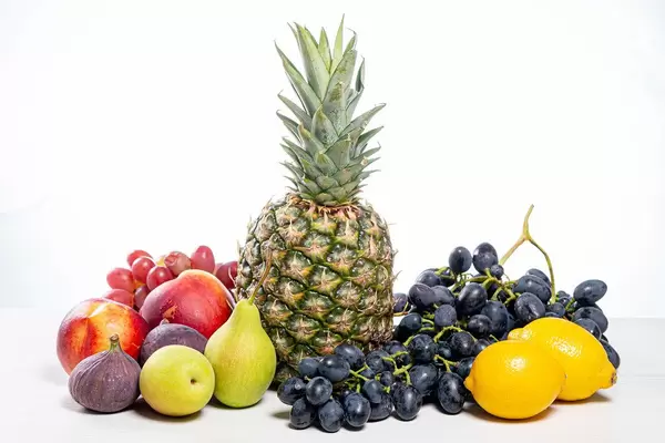 Grapes, pineapple, pears, apples, nectarine, figs and lemons on white background