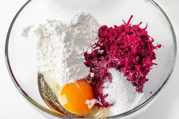 Grated beetroot, flour, sugar, soda and egg in a glass bowl close-up (Flip 2019)