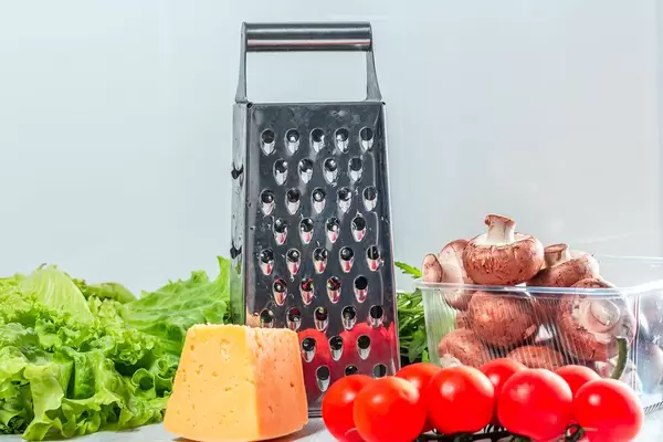 Grater with cheese and fresh vegetables on the kitchen table (Flip 2019)
