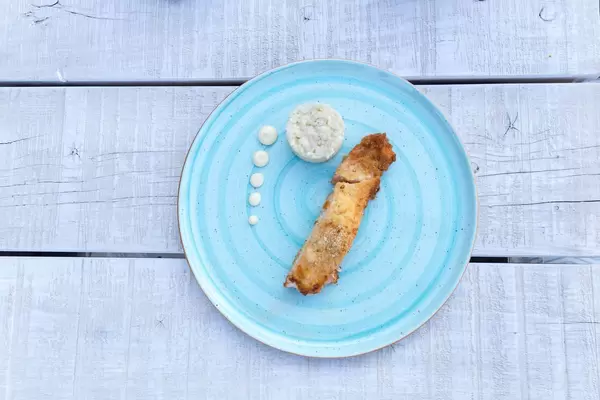 Gratinated salmon with parmesan crust, dark rice and wasabi mayonnaise in a light blue plate