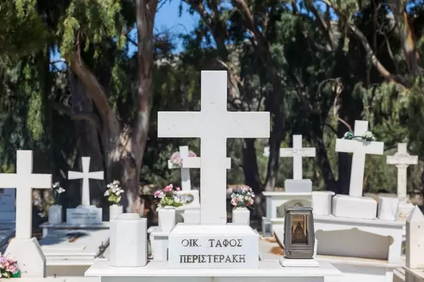 Graves with white marble crosses, flowers and Greek family name. Cemetery of Agios Charalampos, Naxos