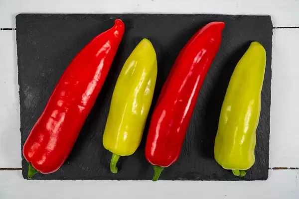 Green and Red fresh Paprikas on the black stone tray (Flip 2020)
