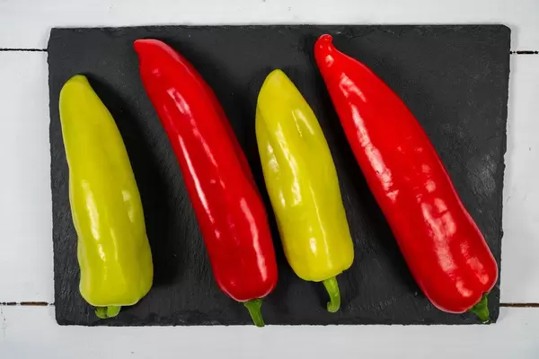 Green and Red fresh Paprikas on the black stone tray