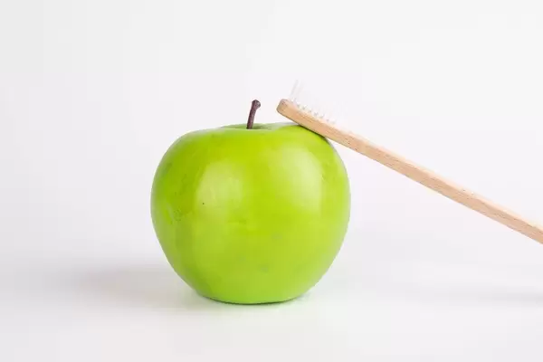 Green apple with wooden toothbrush