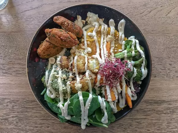Green Bowl Bio-Mittagessen aus dem Edelgrün-Restaurant in Köln, mit Quinoa, Brokkoli, Avocado, Edamame, Spinat, Hummus, Tahini und Parmesan
