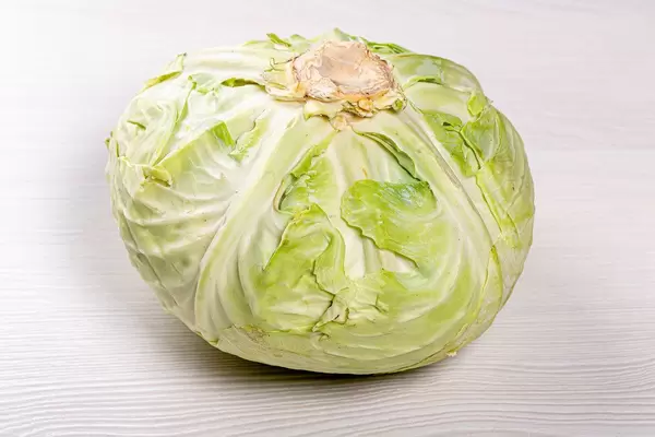 Green fresh raw cabbage on white wooden background