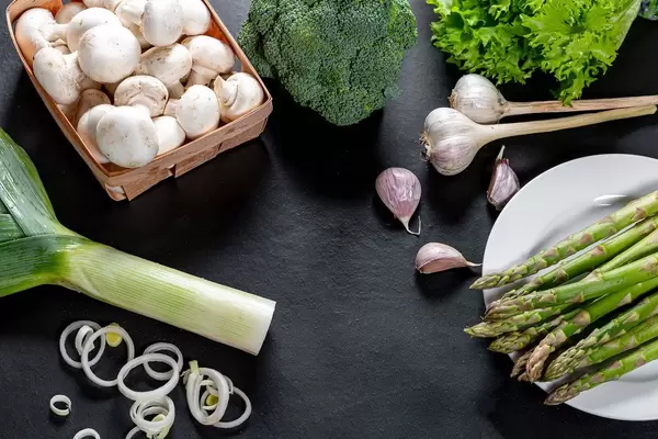 Green fresh vegetables and mushrooms on black background. The concept of cooking healthy food