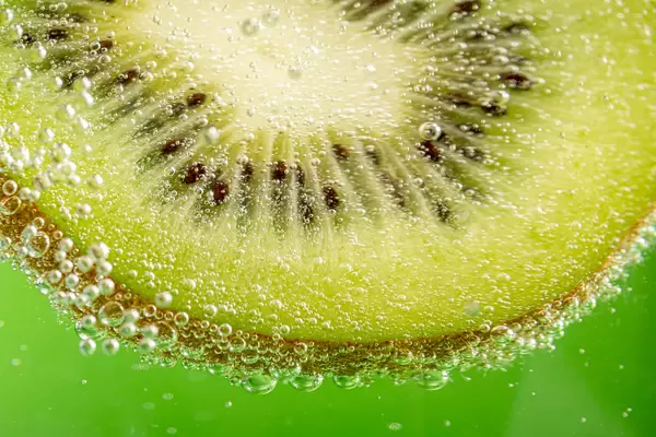 Green fruit background with kiwi slice and bubbles