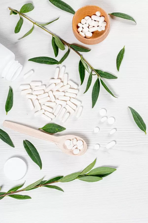 Green leaves and branches with white tablets and capsules. Top view (Flip 2019)