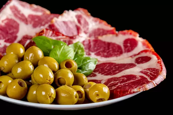 Green pickled pitted olives with sliced smoked meat