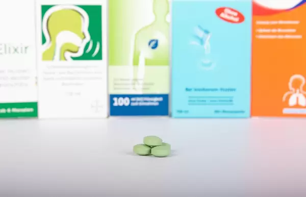 Green pills in front of medicine boxes
