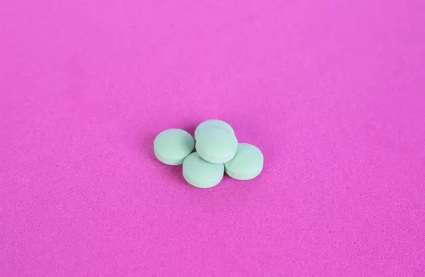 Green pills on pink background
