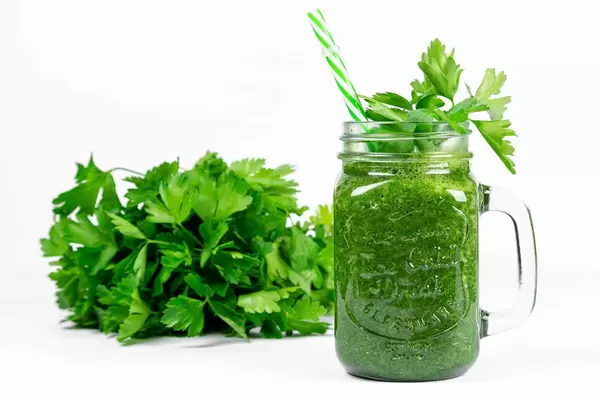 Green smoothie with fresh parsley on a white background