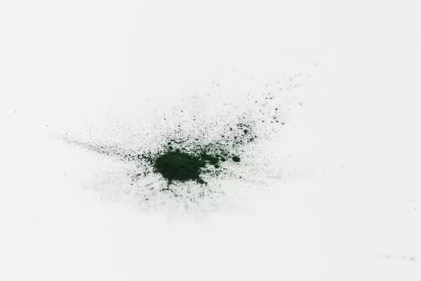 Green spirulina powder spread over a white table