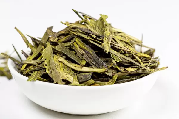 Green tea leaves, in small white bowl