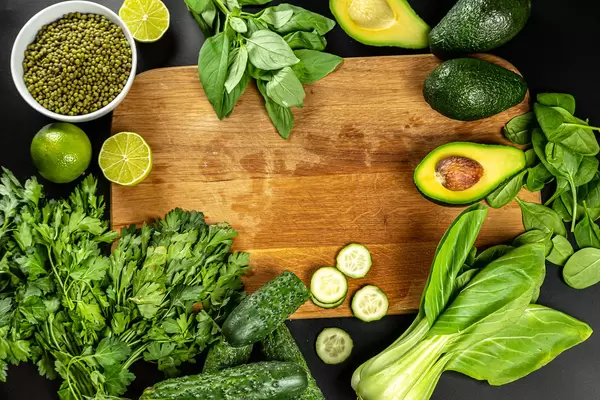 Green vegetables with wooden background-peas, parsley, lime cucumber, avocado