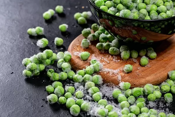 Green young frozen peas with ice closeup