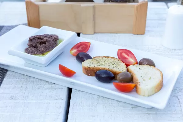 Griechische Vorspeise: schwarze Oliven, Cherrytomaten und fein gehackte Oliven in Olivenöl