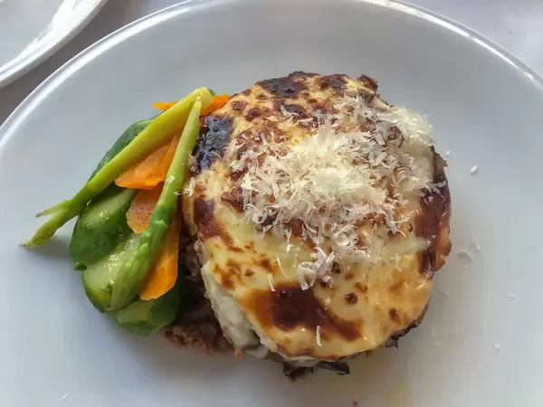 Griechischer Hackfleischauflauf Moussaka, mit Aubergine und Käse, auf einem weißen Teller