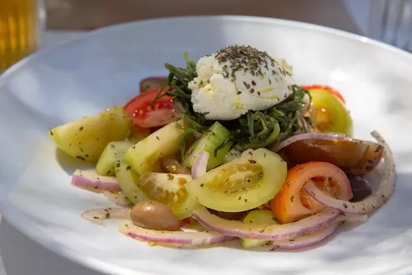 Griechischer Salat mit Kräutern, Zwiebeln, roten und gelben Tomaten, in einem Restaurant auf Paros