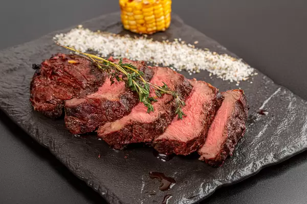 Grilled beef fillet steaks with herbs and spices on dark background